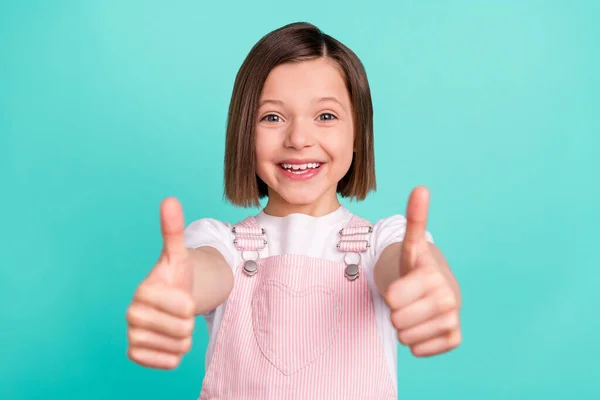 Photo of cheerful happy nice little girl give thumbs up you good job feedback isolated on pastel teal color background