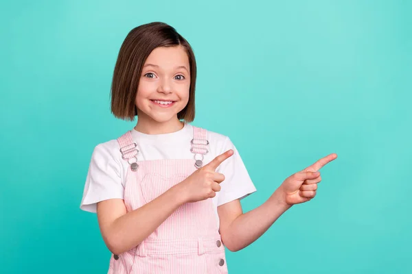 Foto de encantador agradável linda menina apontar os dedos espaço vazio recomendo anúncio isolado no fundo cor teal — Fotografia de Stock