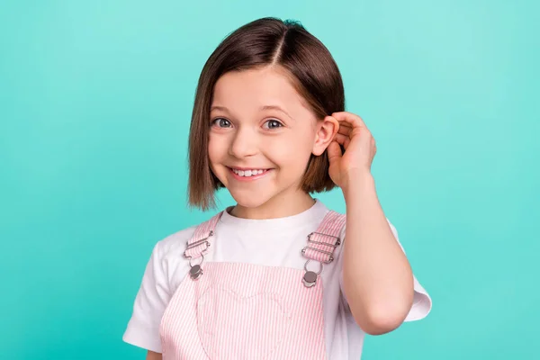 Foto de linda adorable chica de la escuela usar rosa en general sonriente pelo del brazo aislado color verde azulado fondo — Foto de Stock