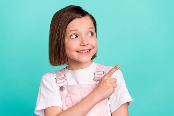 Φωτογραφία από λαμπερό γλυκό κορίτσι σχολείο φορούν ροζ συνολικά χαμογελώντας δείχνοντας δάχτυλο αναζητούν κενό χώρο απομονωμένο φόντο teal χρώμα — Φωτογραφία Αρχείου