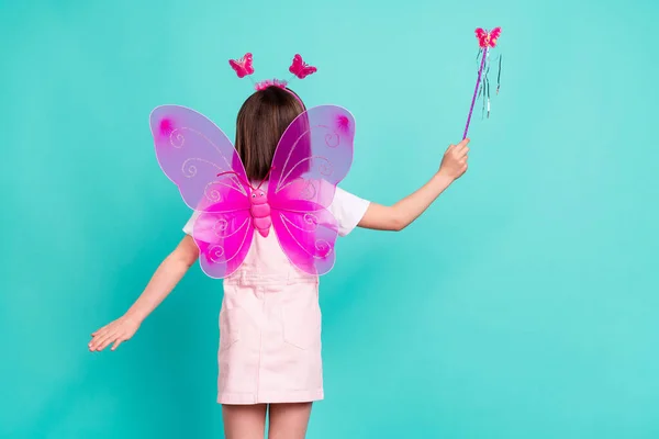 Foto van zoete zorgeloze schoolmeisje gekleed roze algemene vleugels houden fee toverstaf geïsoleerde turquoise kleur achtergrond — Stockfoto