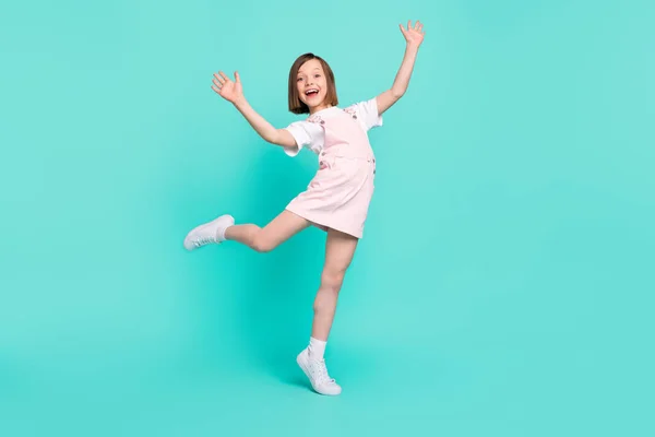 Foto de menina da escola encantadora funky usar rosa geral sorrindo dançando isolado fundo cor teal — Fotografia de Stock