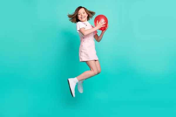 Foto de dulce niña bonita escuela usar rosa en general sonriente saltando alto captura bola roja aislado color verde azulado fondo —  Fotos de Stock
