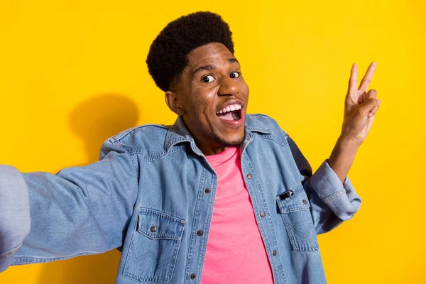 Photo de heureux jeune homme de peau sombre montrer doigts v-signe faire selfie isolé sur fond de couleur jaune — Photo