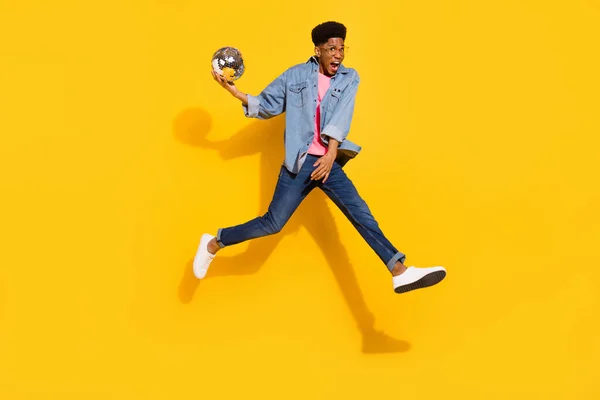 Corpo inteiro foto de alegre jovem afro-americano homem saltar para cima segurar bola disco isolado no fundo de cor amarela — Fotografia de Stock