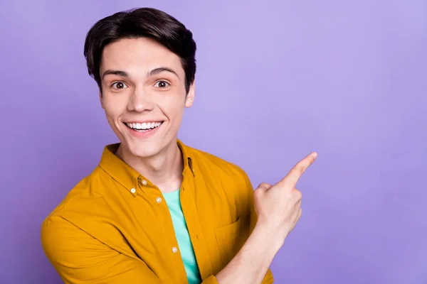 Zdjęcie młodego człowieka szczęśliwy pozytywny uśmiech punkt palec pusty przestrzeń reklama sugerują bezpośrednie izolowane nad fioletowym tle koloru — Zdjęcie stockowe