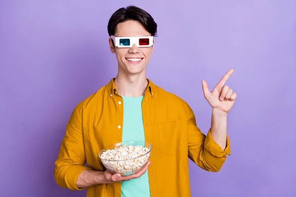 Photo de jeune homme heureux sourire 3d lunettes popcorn regarder film point doigt espace vide ad conseils isolés sur fond de couleur violette — Photo