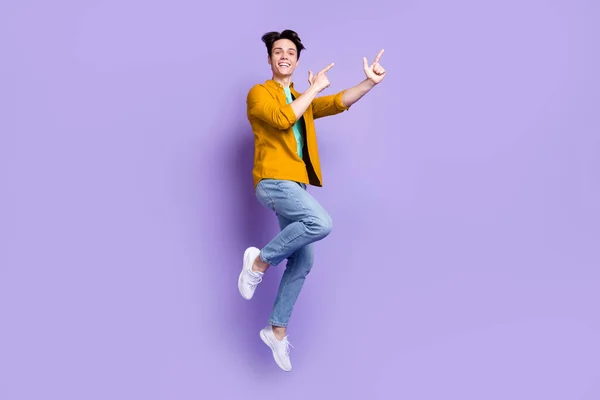 쿨 브루 네 막 남자가 점프하는 사진 전체가 보라색 배경에 고립된 빈 우주복 청바지를 입고 있음을 나타낸다 — 스톡 사진