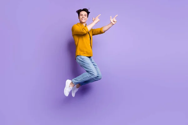 전체 크기 프로필 사진 행복 한 젊은 남성의 긍정적 인 미소 점프 점프 보라색 배경 위에 분리 된 손가락빈 우주 광고 — 스톡 사진