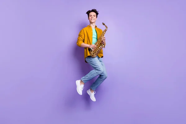 Foto em tamanho completo de funky morena millennial cara pular com sax desgaste camisa jeans isolado no fundo cor violeta — Fotografia de Stock