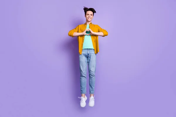 フルサイズ写真の若い男幸せな正の笑顔ジャンプアップショー指ハートシンボル孤立上紫色の背景 — ストック写真