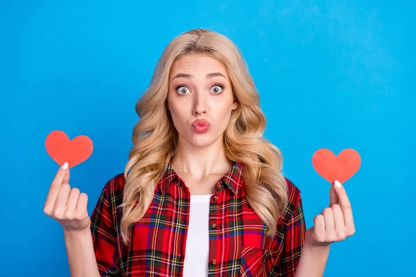 Foto di flirty adorabile giovane signora indossare camicia a quadri in possesso di due cuori rossi labbra imbronciato isolato sfondo di colore blu — Foto Stock