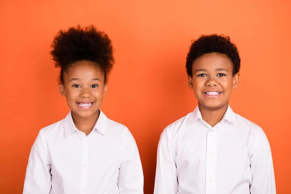 긍정적 인 미소를 짓는 행복 한 젊은 아프리카 아이들의 사진 오렌지 색 배경 위에 고립된 흰색 셔츠를 입고 있다 — 스톡 사진