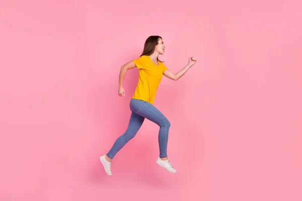 Profilo completo del corpo foto di divertente bruna capelli millenaria signora salto indossare giallo t-shirt jeans isolato su sfondo rosa — Foto Stock