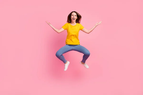 Foto de adorable mujer impresionada vestida camiseta amarilla saltando brazos de alta medida espacio vacío aislado color rosa fondo —  Fotos de Stock