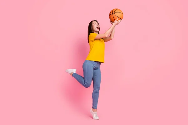 Foto de la encantadora joven dama usar camiseta amarilla lanzando pelota de baloncesto aislado color rosa fondo — Foto de Stock