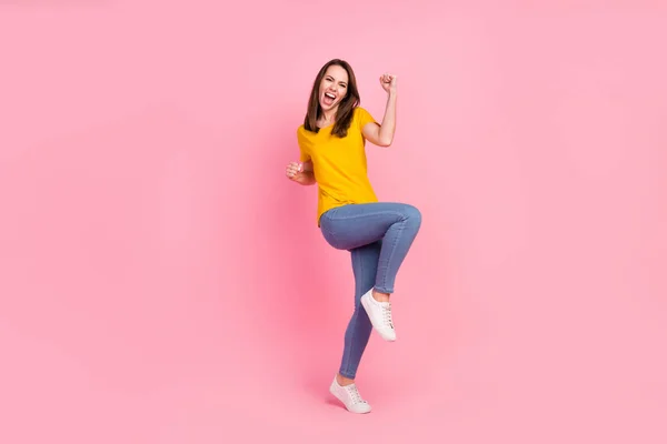 Full body foto van hooray brunette haar jonge dame handen vuisten dragen gele t-shirt jeans geïsoleerd op roze kleur achtergrond — Stockfoto