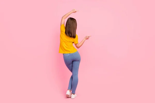 Foto de magro bonito jovem senhora desgaste amarelo t-shirt de pé para trás apontando polegares vazio espaço isolado cor rosa fundo — Fotografia de Stock