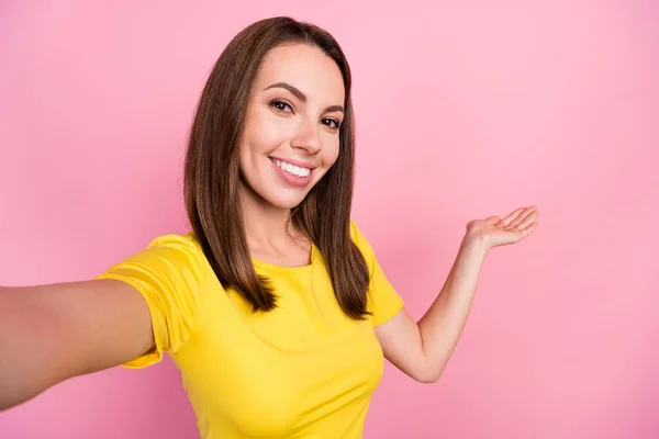 Kuva makea brunette hiukset nuori nainen do selfie pidä tyhjää tilaa kulumista keltainen t-paita eristetty vaaleanpunainen väri tausta — kuvapankkivalokuva
