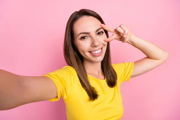 Foto de encantador bonito jovem senhora desgaste amarelo t-shirt sorrindo gravação vídeo v-sign capa olho isolado cor de rosa fundo — Fotografia de Stock