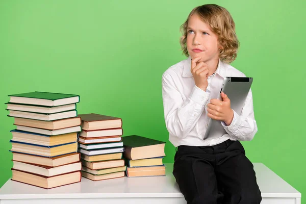 Foto de piense poco rubio niño mantenga tableta libro usar camisa blanca aislada sobre fondo de color verde —  Fotos de Stock
