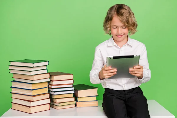 Foto de pequeño niño rubio lindo mantenga la tableta con vestido de libro camisa blanca aislada sobre fondo de color verde — Foto de Stock