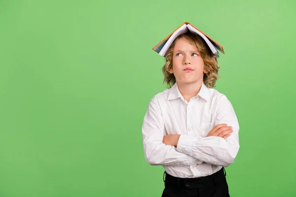 Foto di piccolo ragazzo biondo pazzo incrociato braccia libro sulla testa indossare camicia bianca isolato su sfondo di colore verde — Foto Stock