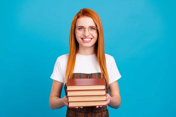 Porträt eines attraktiven, fröhlichen Nerd-Mädchens, das Buchmaterialien in Händen hält, isoliert über hellblauem Hintergrund — Stockfoto