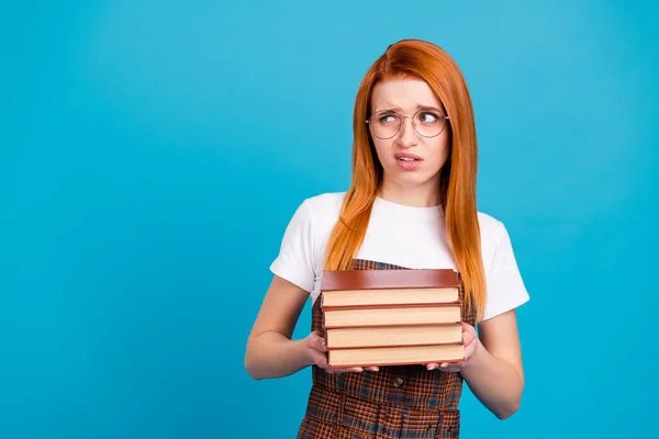 Foto von zweifelhaft misstrauisch Frau gekleidet karierten Kleid Brille hält Stapel Buch leeren Raum isoliert blaue Farbe Hintergrund — Stockfoto