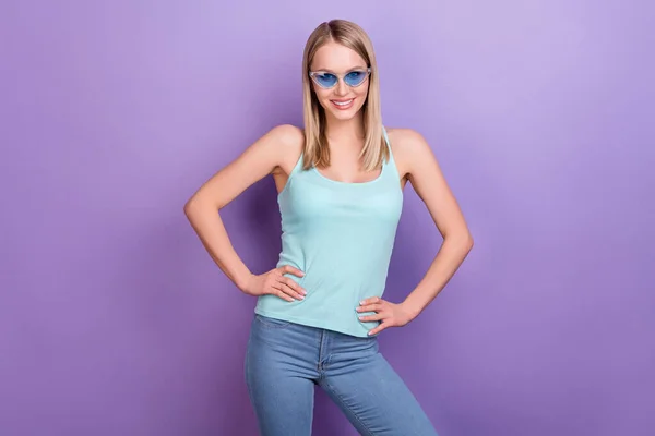 Photo of cool blond millennial lady stand wear blue top eyewear jeans isolated on violet color background — Stock Photo, Image