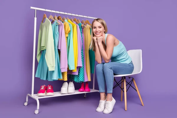 Ganzkörper-Foto von niedlichen blonden Millennial Dame sitzen im Kleiderschrank tragen teal top Jeans Turnschuhe isoliert auf violettem Hintergrund — Stockfoto