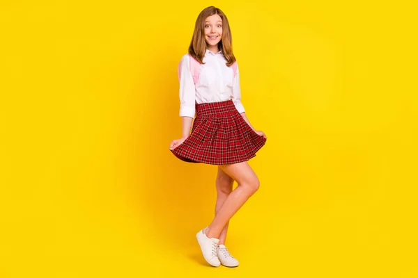 Küçük güzel bir kızın tam boy fotoğrafı sarı arka planda izole edilmiş etek çantalı spor ayakkabılar giyiyor. — Stok fotoğraf