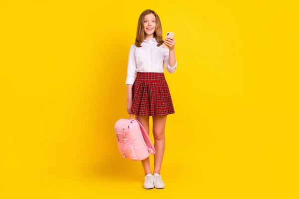 Full size foto di cute piccola ragazza tenere telefono usura camicia gonna borsa scarpe da ginnastica isolato su sfondo giallo — Foto Stock