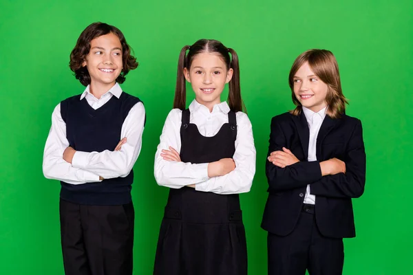 Portrait of three attractive cheerful kids folded arms academic lesson isolated over bright green color background — Stock Photo, Image