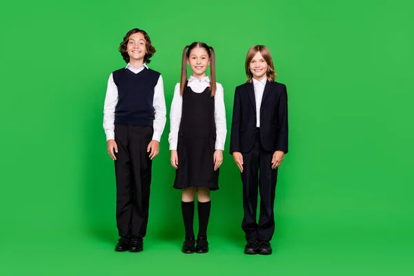 Взгляд в полный рост на привлекательных веселых детей-одноклассников, изолированных на ярко-зеленом фоне — стоковое фото