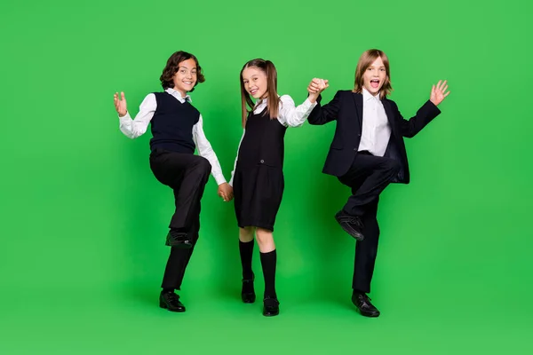 stock image Full size photo of funny little girl boys hold hands go wave wear school uniform isolated on green background