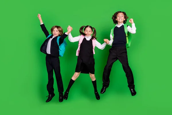 Volledige lichaam foto van grappige kleine meisje jongens springen dragen school uniform schoenen geïsoleerd op groene achtergrond — Stockfoto