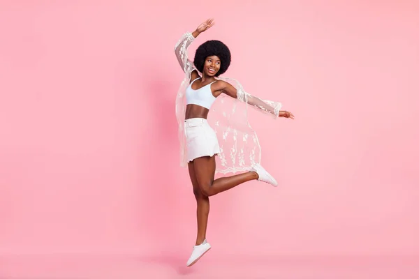 Full length photo of cheerful young dark skin woman look empty space jump up isolated on pink color background — Fotografia de Stock