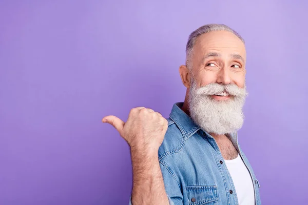Photo of charming pretty mature man dressed denim outfit looking pointing back finger empty space isolated purple color background — Foto de Stock