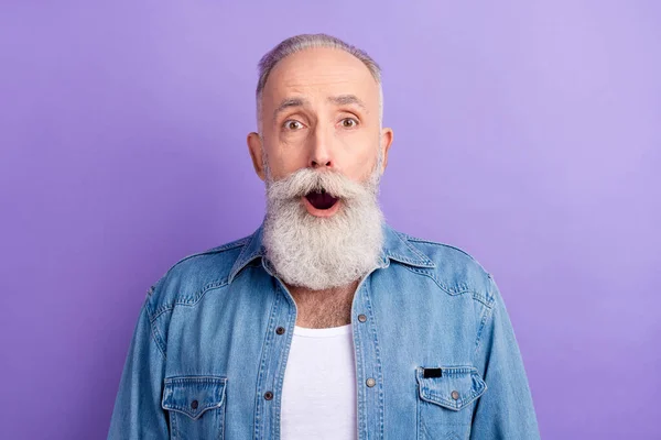 Foto van ernstige geschokte leeftijd heer dragen jeans shirt open mond grote ogen geïsoleerde violette kleur achtergrond — Stockfoto