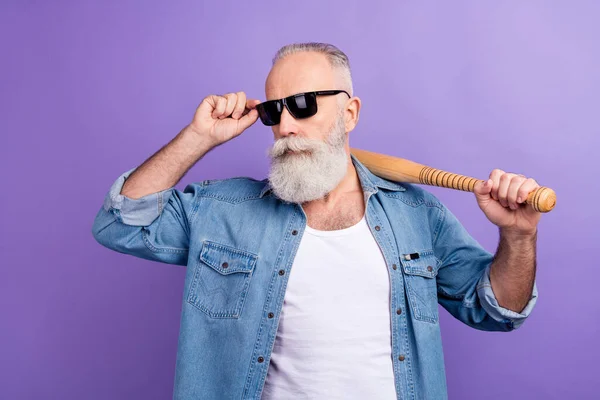 Photo of aged man serious confident hold baseball bat sportive hand touch sunglass isolated over violet color background — Stockfoto