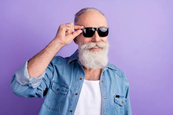 Фото красивого літнього чоловіка щаслива позитивна посмішка впевнена рука дотик сонцезахисний окуляри ізольовані на фіолетовому кольоровому фоні — стокове фото