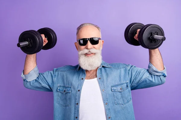 Photo of elderly sportsman bodybuilding muscles strong dumbells isolated over purple color background —  Fotos de Stock