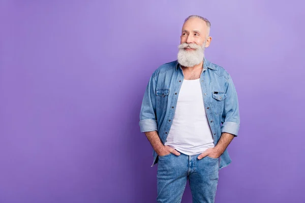 Photo of aged man happy positive smile hands in pocket look empty space isolated over purple color background — Stockfoto