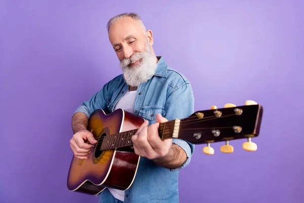 Profiel zijkant foto van de oude man gelukkig positieve glimlach spelen gitaar muziek liefhebber geïsoleerd over paarse kleur achtergrond — Stockfoto