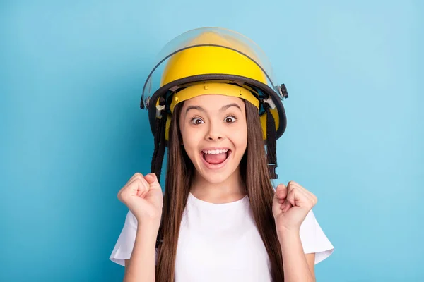 Foto van jonge school meisje gelukkig positieve glimlach dragen helm vreugde overwinning vuisten handen geïsoleerd over blauwe kleur achtergrond — Stockfoto