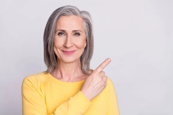 Photo of happy smiling beautiful mature woman point finger copyspace advertisement isolated on grey color background — Fotografia de Stock