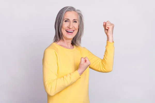 Foto van gelukkig opgewonden goed humeur vrolijke volwassen vrouw verhogen vuisten in overwinning triomf geïsoleerd op grijze kleur achtergrond — Stockfoto