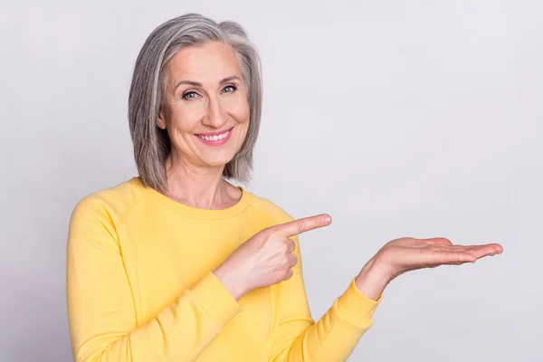 Photo of happy cheerful smiling grandmother advertising recommending product isolated on grey color background — Fotografia de Stock