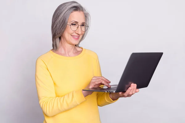 Photo of happy cheerful positive mature businesswoman in glasses working in laptop isolated on grey color background — Photo